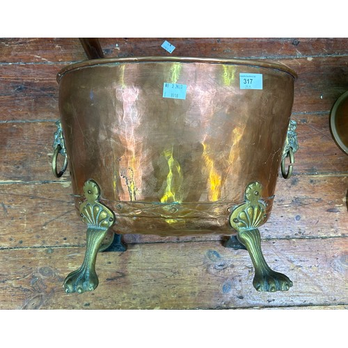 317 - A copper coal bucket with brass lions mask ring handles and raised on lions paw feet, 43cm long