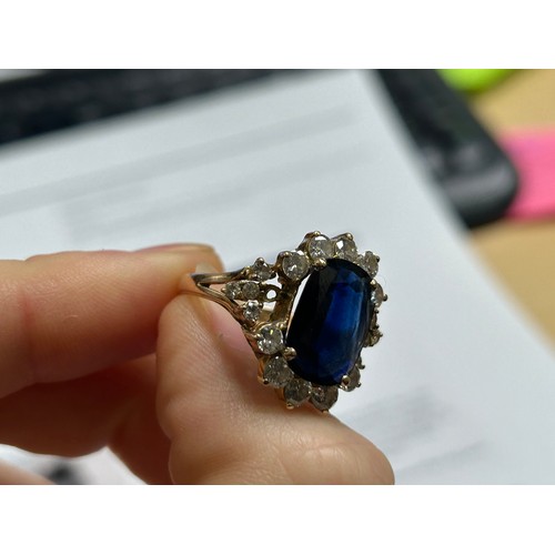 197 - A Sapphire and Diamond cluster ring, 14ct gold shank with open scrollwork, centrally claw-set an ova... 