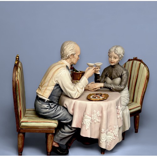 19 - A Capodimonte figural group titled ‘Anniversario’ by Sandro Maggioni, 1979, of a couple sat across f... 