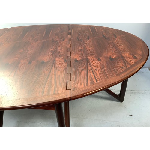 423 - A mid-century rosewood oval drop leaf dining table, the top with square sectioned piano hinges to ea... 