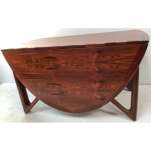 423 - A mid-century rosewood oval drop leaf dining table, the top with square sectioned piano hinges to ea... 