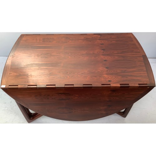 423 - A mid-century rosewood oval drop leaf dining table, the top with square sectioned piano hinges to ea... 