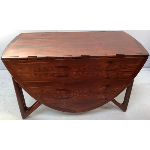 423 - A mid-century rosewood oval drop leaf dining table, the top with square sectioned piano hinges to ea... 