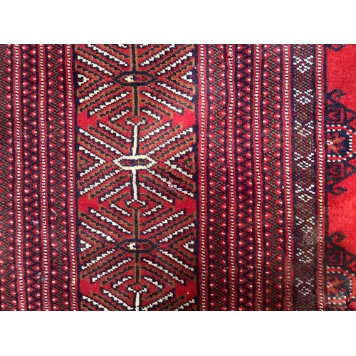 406 - A hand-knotted wool Bokhara Rug, worked with a field of stylised guls to a red ground, within a bord... 