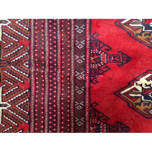 406 - A hand-knotted wool Bokhara Rug, worked with a field of stylised guls to a red ground, within a bord... 