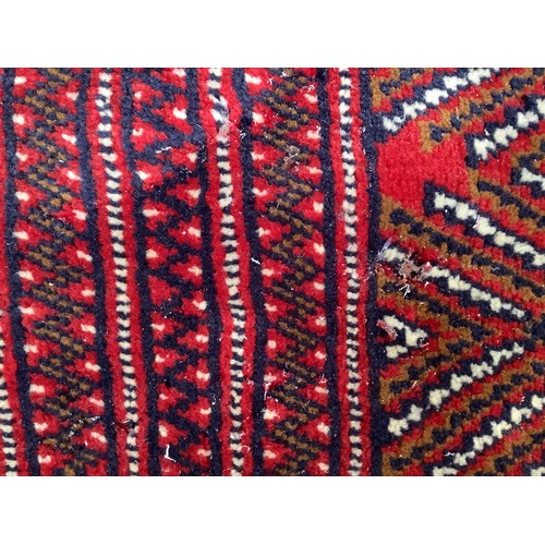 406 - A hand-knotted wool Bokhara Rug, worked with a field of stylised guls to a red ground, within a bord... 