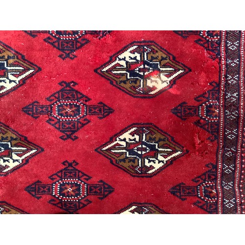 406 - A hand-knotted wool Bokhara Rug, worked with a field of stylised guls to a red ground, within a bord... 