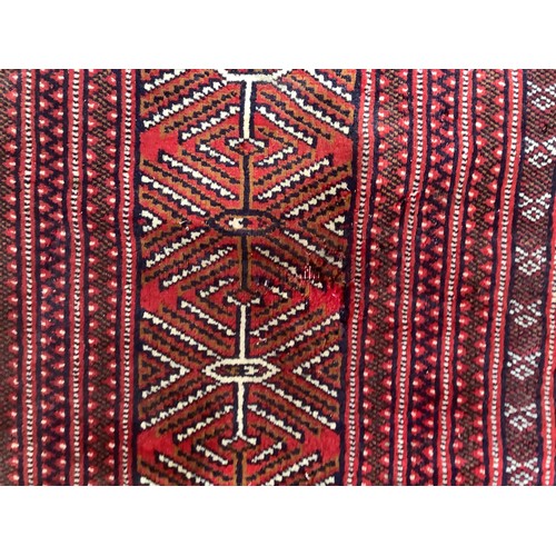 406 - A hand-knotted wool Bokhara Rug, worked with a field of stylised guls to a red ground, within a bord... 