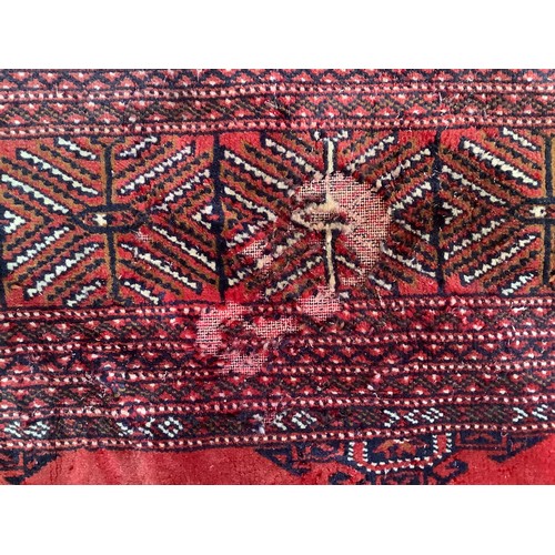 406 - A hand-knotted wool Bokhara Rug, worked with a field of stylised guls to a red ground, within a bord... 