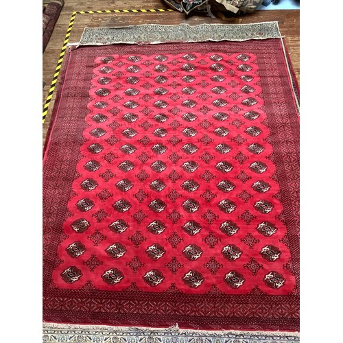 408 - A hand-knottd woollen Bokhara carpet, typically worked with a field of stylised guls to a red ground... 