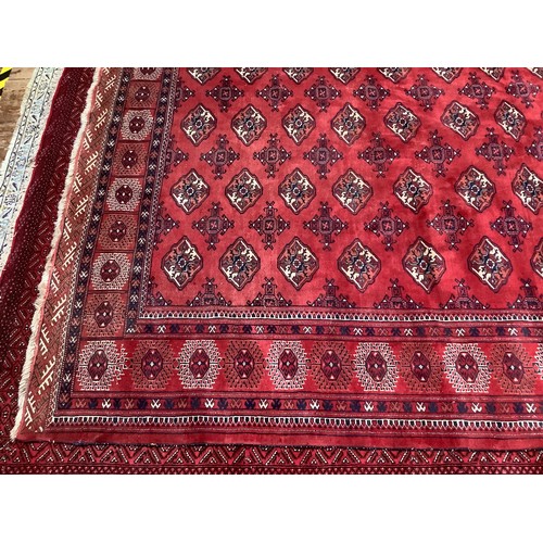 409 - A hand-knotted wool Bokhara carpet, typically worked with stylised guls to a red ground within a bor... 