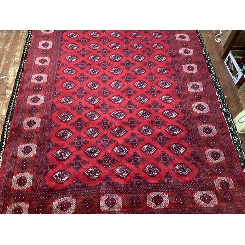 412 - A hand-knotted wool Bokhara carpet, worked with a field of stylised guls and herati to the red field... 