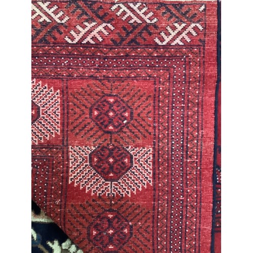 412 - A hand-knotted wool Bokhara carpet, worked with a field of stylised guls and herati to the red field... 