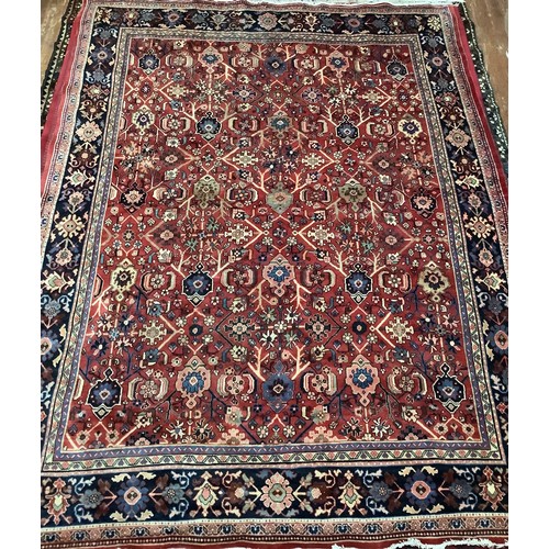 413 - A hand-knotted wool garden carpet, with with a field of stylised flowers to deep red ground, within ... 