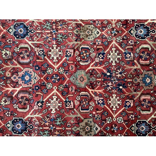 413 - A hand-knotted wool garden carpet, with with a field of stylised flowers to deep red ground, within ... 