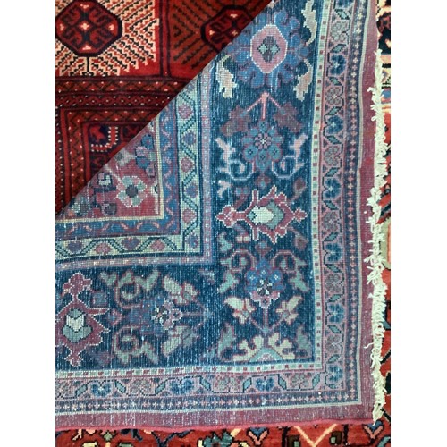 413 - A hand-knotted wool garden carpet, with with a field of stylised flowers to deep red ground, within ... 