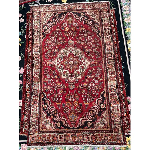 418 - A Persian hand-knotted wool rug, worked with a central stylised floral medallion to a red ground, wi... 