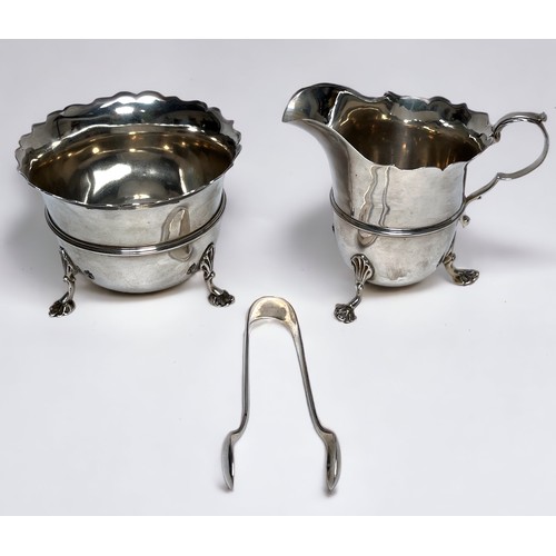 68 - A late Victorian silver cream jug and sugar bowl with tongs, serpentine cut rims on scrolled Anthemi... 