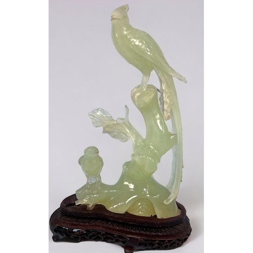 53 - A modern carved jade figure of a pheasant and smaller bird on a branch, raised on carved wooden pede... 