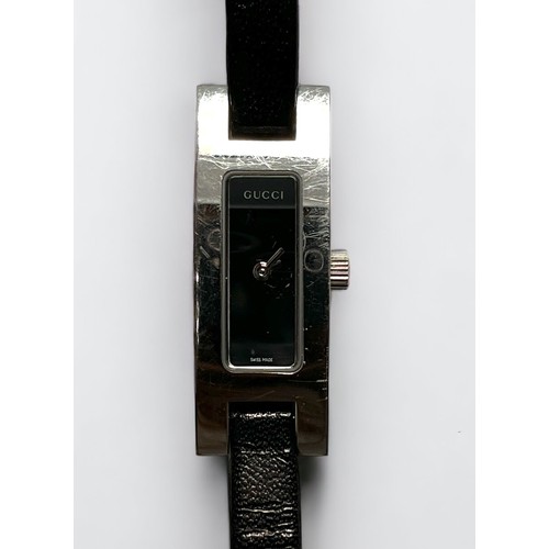 107 - A ladies stainless steel Gucci 3900L wristwatch, the black enamel dial with branding, on slim black ... 