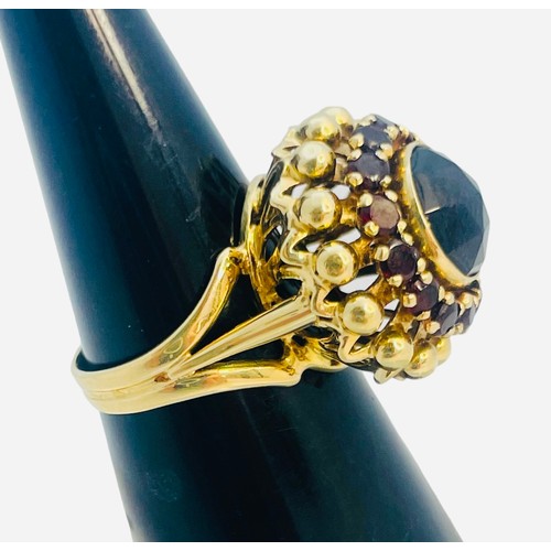 145 - An 14ct yellow gold dress ring, set with a round faceted garnet to the centre, with 14 x small round... 