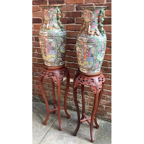 62 - A pair of large 20th century famille rose baluster vases, each decorated in Canton enamels with pane... 