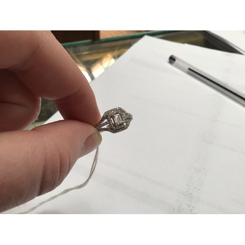 136 - An 18ct white gold diamond ring, set with a central emerald cut diamond, measuring 5mm x 6mm, surrou... 