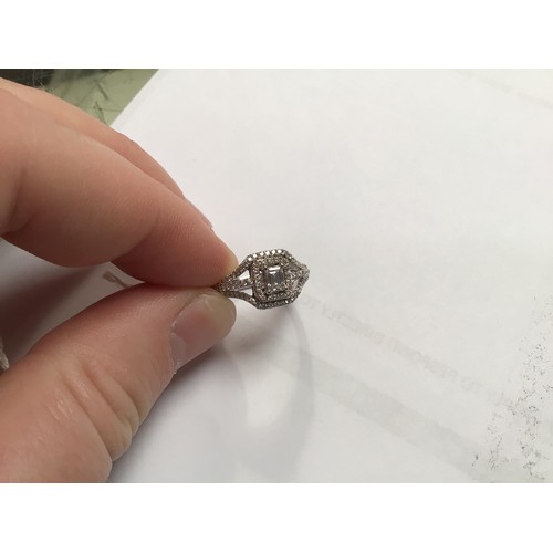 136 - An 18ct white gold diamond ring, set with a central emerald cut diamond, measuring 5mm x 6mm, surrou... 