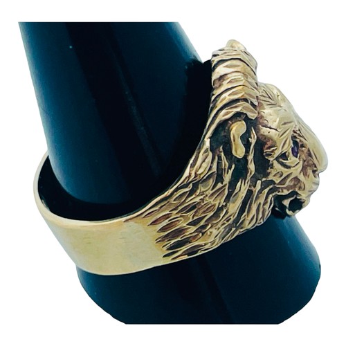 166 - A 9ct yellow gold lions head ring, with 2 x small faceted red stones in eyes, weighs 8.6 grams.