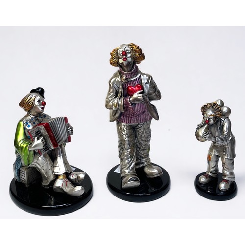 48 - Three silvered figures of clowns by Mida’s, one holding a love heart, another playing an accordion a... 