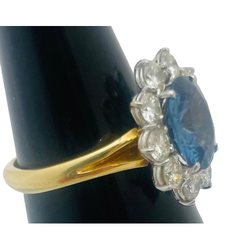 205 - An 18ct yellow gold dress ring, set with an oval shaped, blue topaz to the centre, surrounded by 10 ... 