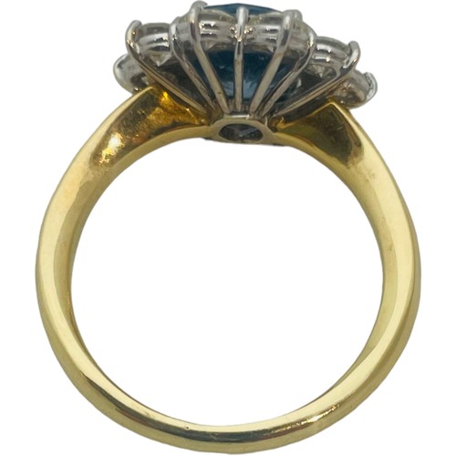 205 - An 18ct yellow gold dress ring, set with an oval shaped, blue topaz to the centre, surrounded by 10 ... 