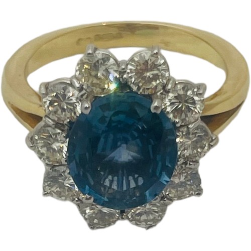 205 - An 18ct yellow gold dress ring, set with an oval shaped, blue topaz to the centre, surrounded by 10 ... 