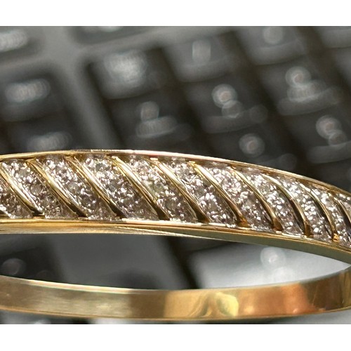 164 - A 9ct yellow gold bangle, illusion set with 33 x small round diamonds, estimated total diamond weigh... 