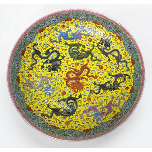 62 - A Chinese porcelain charger, incised and decorated in polychrome enamels, with nine dragons, yellow ... 