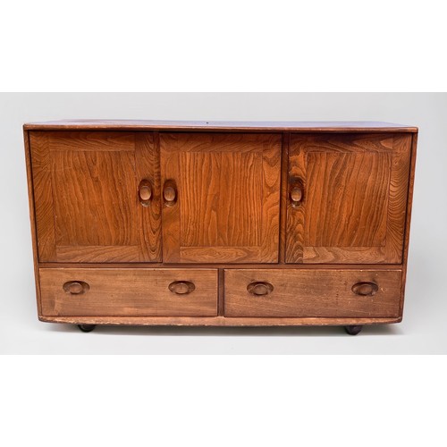 567 - A blonde elm and beech Ercol sideboard, model 366, with three cupboard doors, above two drawers, rai... 