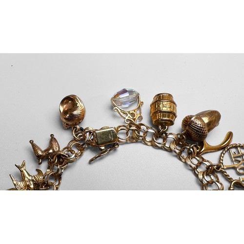 144 - A 9ct gold bracelet with 22 x various gold charms, including a dolphin, a cat, an acorn, and a bell ... 