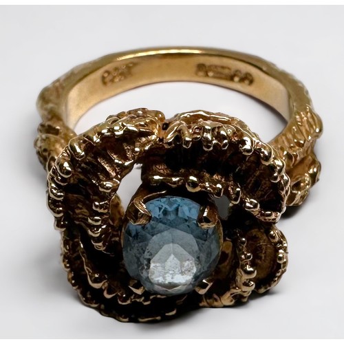 192 - A 9ct gold dress ring, of stylised floral design, set with an oval faceted blue stone to the centre,... 