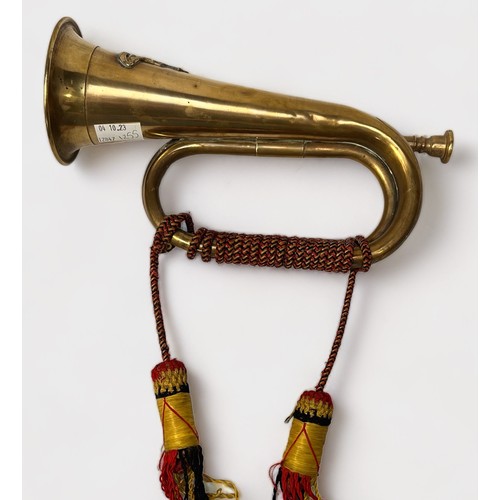 486 - A brass bugle with Royal Artillery mounted badge and red, yellow and black plaited cord and tassels