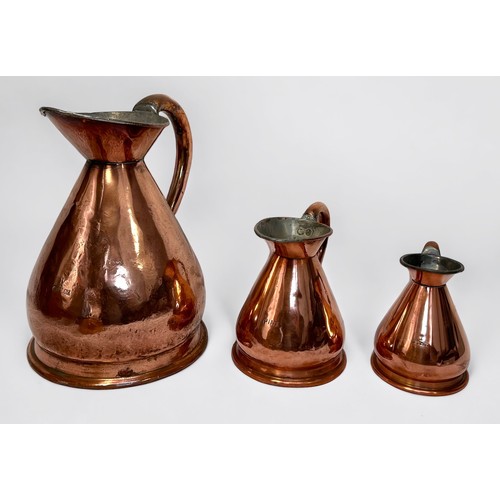 521 - A harlequin set of three graduated copper haystack jugs, the largest measuring 1/2 gallon, including... 