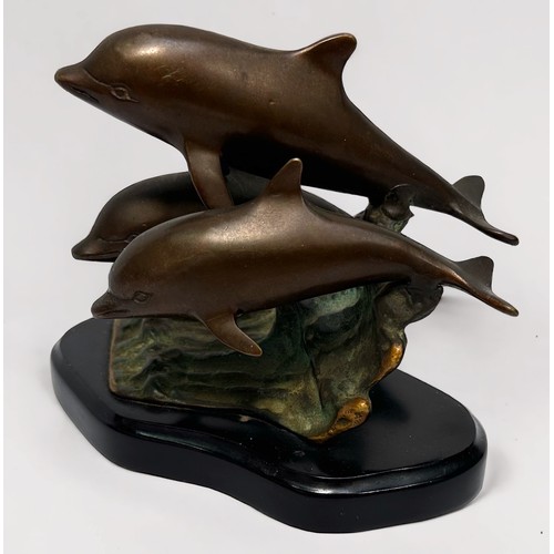 324 - A patinated cast bronze figure group of three leaping dolphins on the crest of a wave, on plinth bas... 