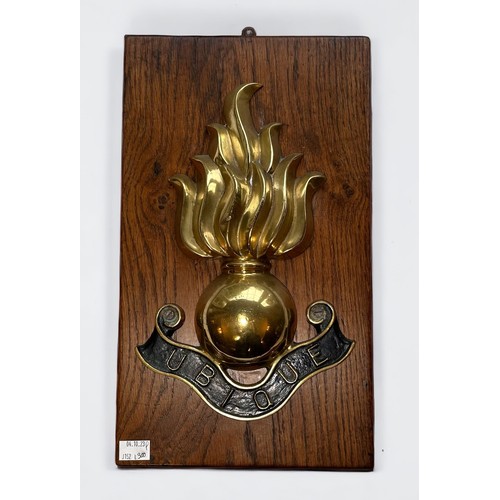 511 - A large Royal Artillery brass grenade badge and 'Ubique' motto, mounted on wooden plaque