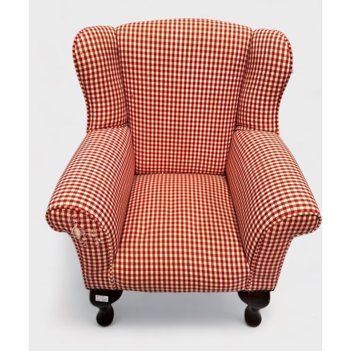 518 - A Child's wingback armchair with red check upholstery, on carbiole supports (a/f)