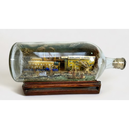 425 - A superb diorama ship-in-a-bottle, with six various sailing barges, freighters and tugs etc, against... 