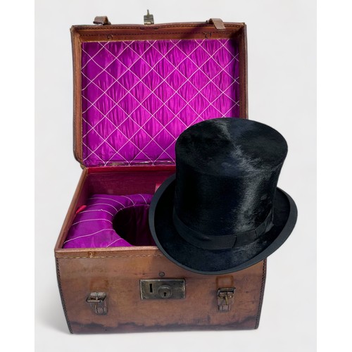 360 - A vintage top hat with coat of arms to interior, housed in fitted and lined tan leather, lockable tr... 