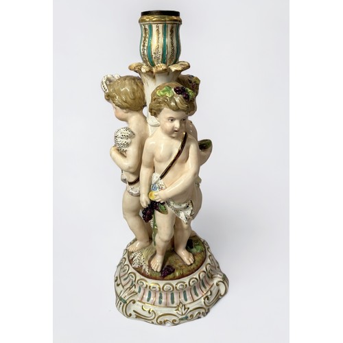 31 - A 19th century continental porcelain figural candlestick, modelled with three Putti emblematic of th... 