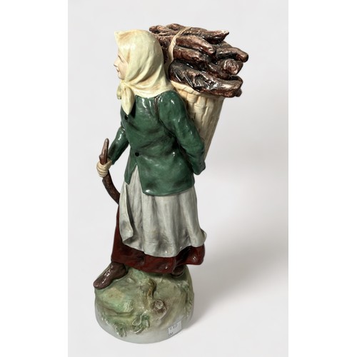 6 - A Royal Dux pottery figure of a female 'faggot gatherer,' modelled with head-scarf and a loaded bask... 