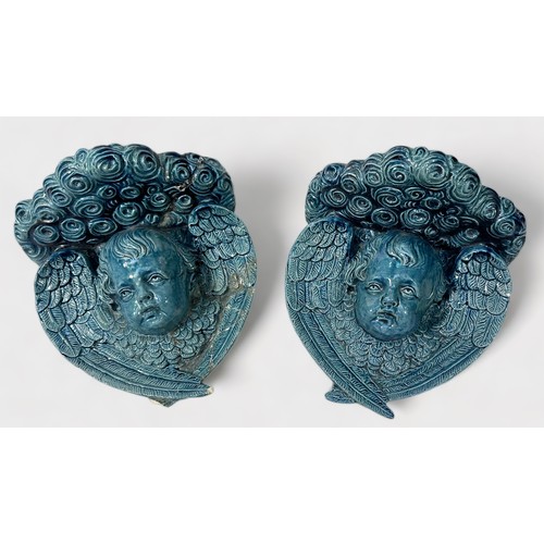 40 - A pair of 19th century blue-blazed majolica wall brackets moulded with a winged-cherub masks, (one r... 