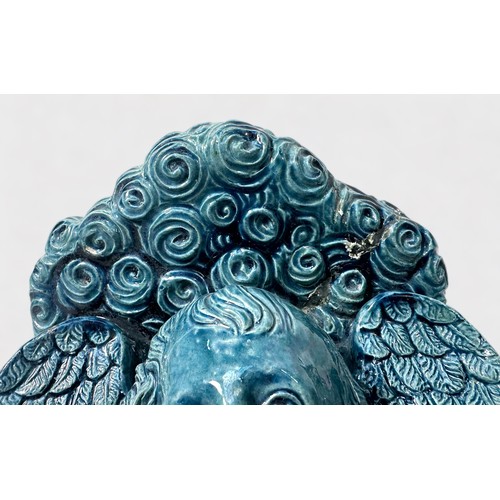 40 - A pair of 19th century blue-blazed majolica wall brackets moulded with a winged-cherub masks, (one r... 