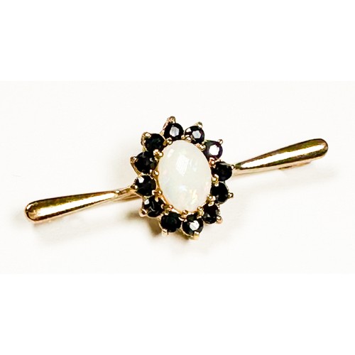 173 - A 9ct gold bar-brooch, claw set to the centre with an oval-shaped opal, surrounded by 12 x round fac... 